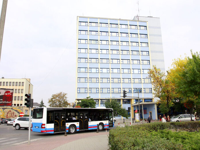 Autobus na tle błękitnego, 10-piętrowego budynku