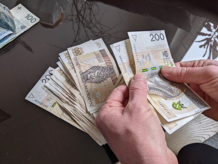 Zdjęcie dłoni trzymających banknoty o nominale 200 zł