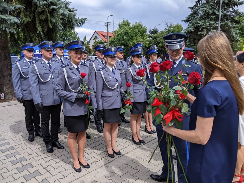 Policjantki i policjanci ubrani na galowo stoją w trzech rzędach.