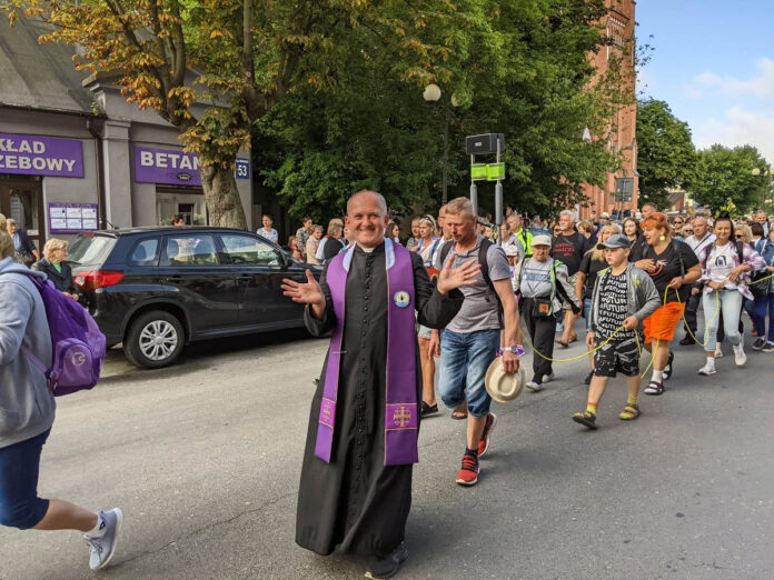 Ksiądz na tle pielgrzymujących osób