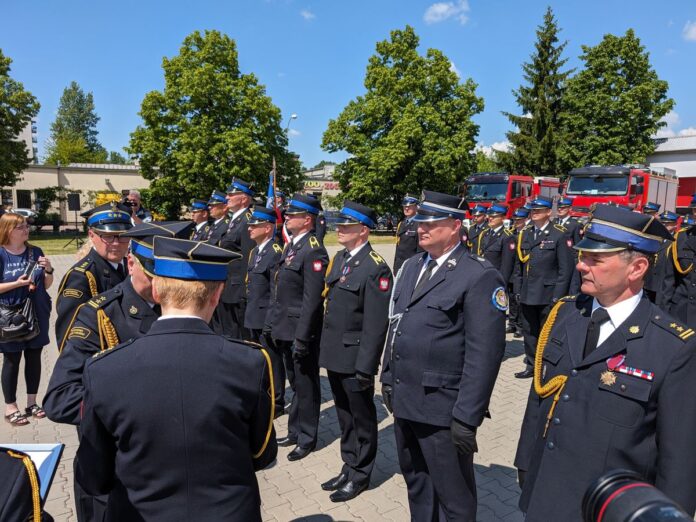 Strażacy ubrani w stroje galowe stoją w rzędach