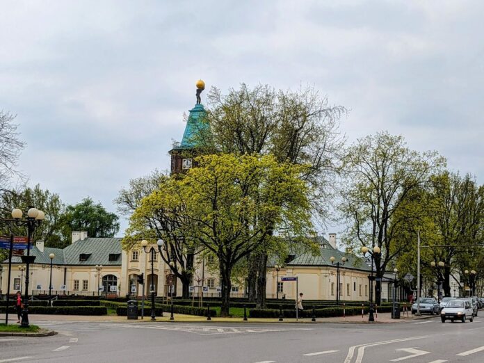 Budynek z figurą Atlasa na dachu za drzewami