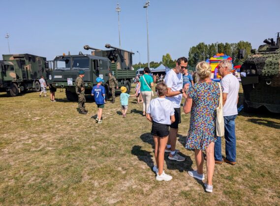 Grupa osób z pojazdami wojskowymi w tle