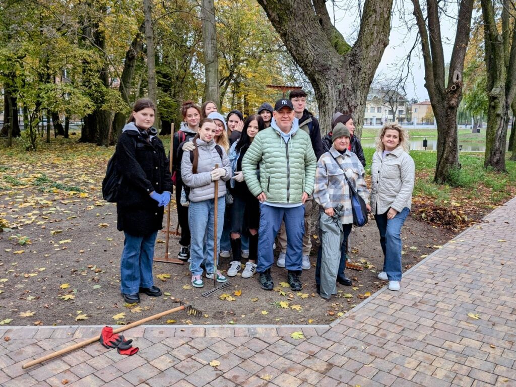 Grupa osób stoi w parku pod drzewem