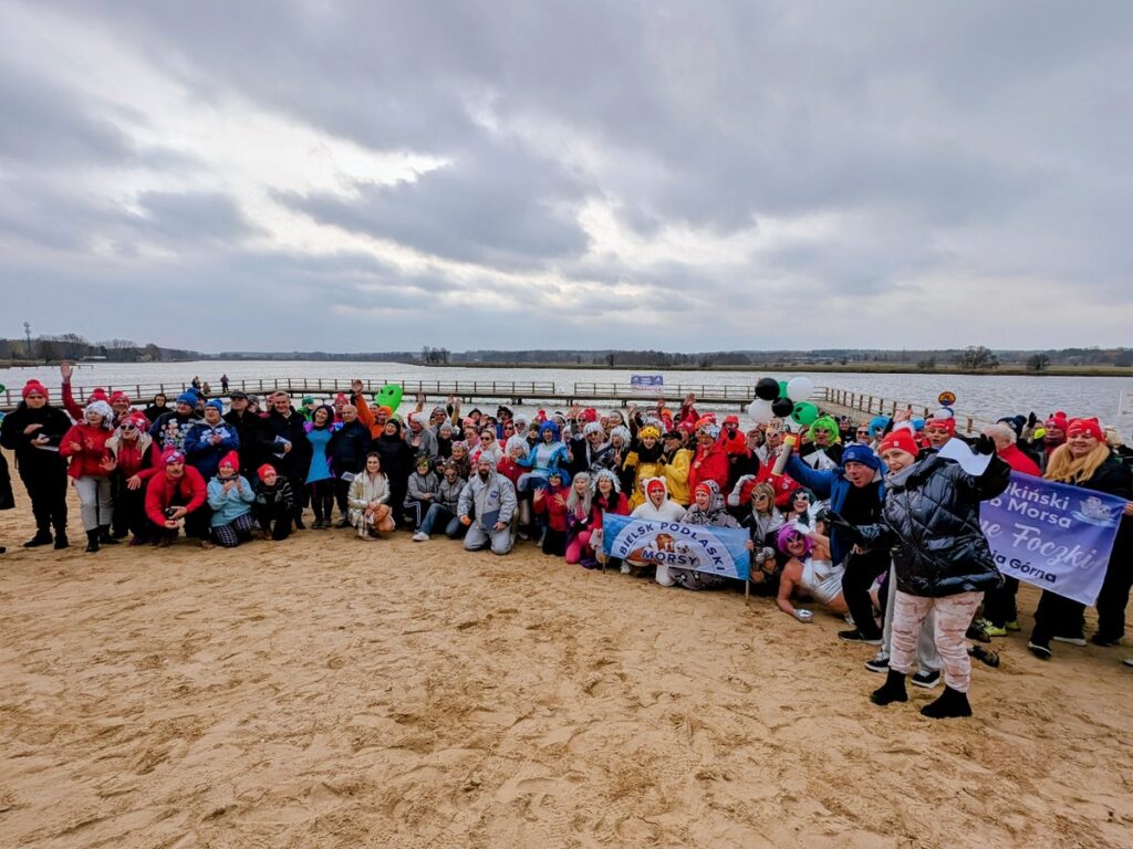 Kilkadziesiąt osób w przebraniach robi grupowe zdjęcie na plaży