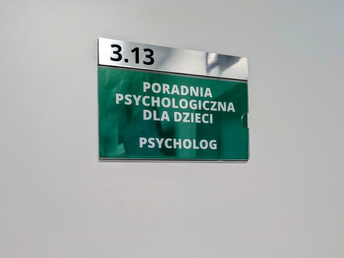 Zielona tabliczka na drzwiach z napisem poradnia psychologiczna dla dzieci