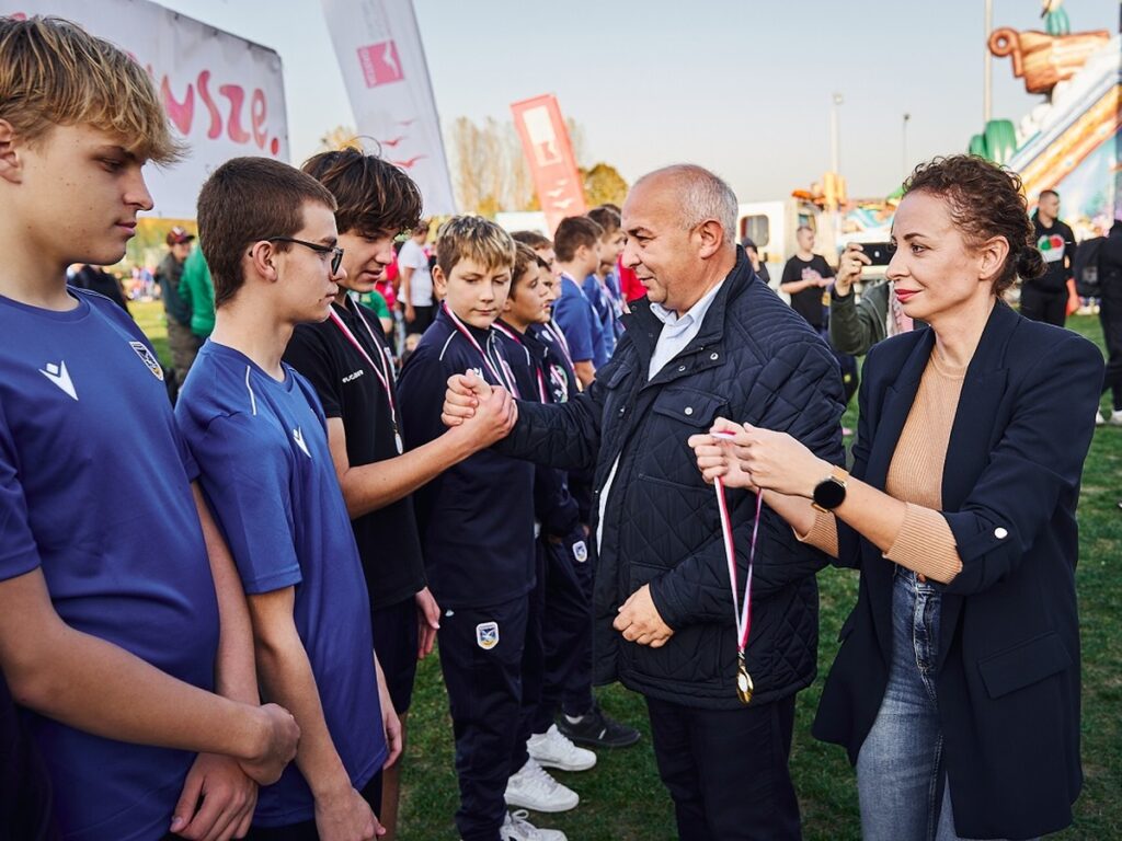 Mężczyzna i kobieta dekorują medalami młodych zawodników