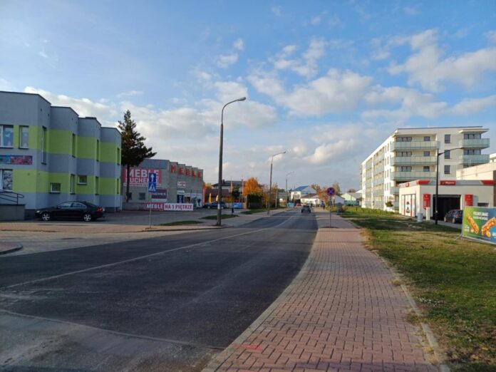 Ulica z asfaltową nawierzchnią, w mieście z chodnikami po obu stronach