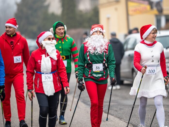 Pięć osób przebranych w mikołajkowe stroje uprawia nordic walking.