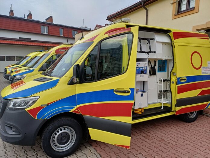 Zespół karetek stojących przed budynkiem, przygotowanych do interwencji medycznych.