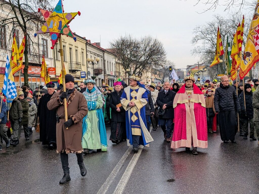 Mężczyźni przebrani w kolorowe szaty idą na czele barwnego orszaku trzech króli.