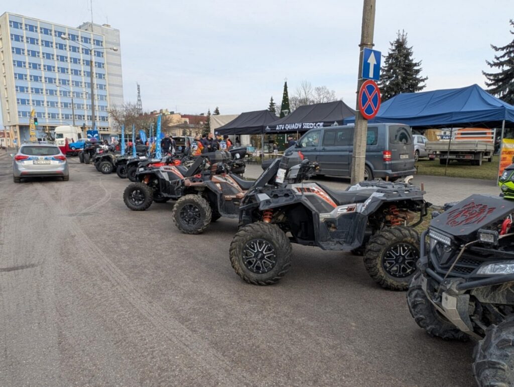 Zestaw quadów stojących w rzędzie na parkingu, gotowych do jazdy w terenie.