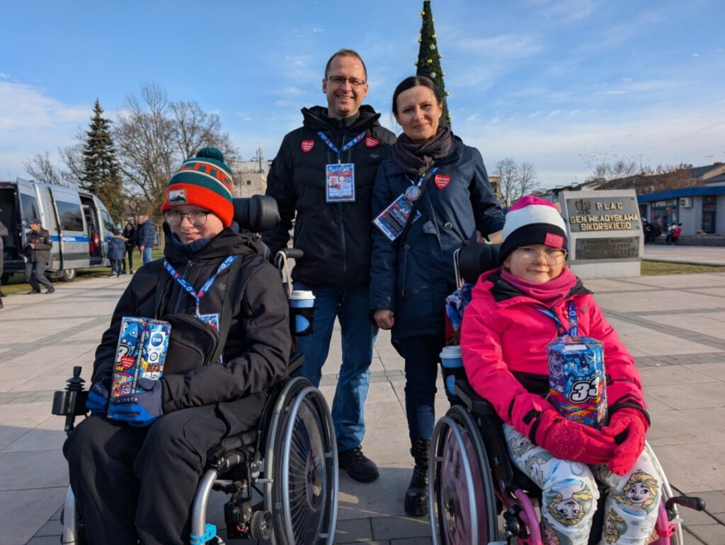 Rodzina pozująca do zdjęcia przed budynkiem, uśmiechnięta i zadowolona, uchwycona w radosnym momencie.